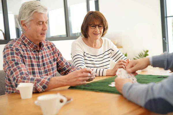 Senior friends at home playing cards