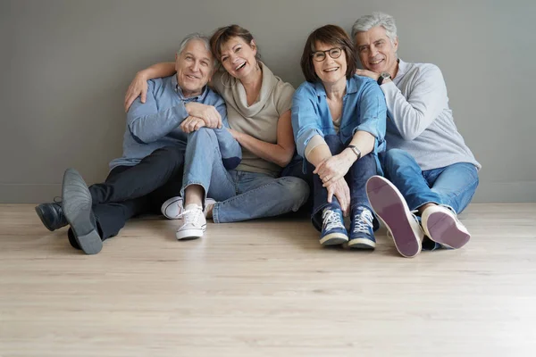 Gruppe Lykkelige Eldre Mennesker Som Sitter Gulvet Mot Veggen Isolert – stockfoto