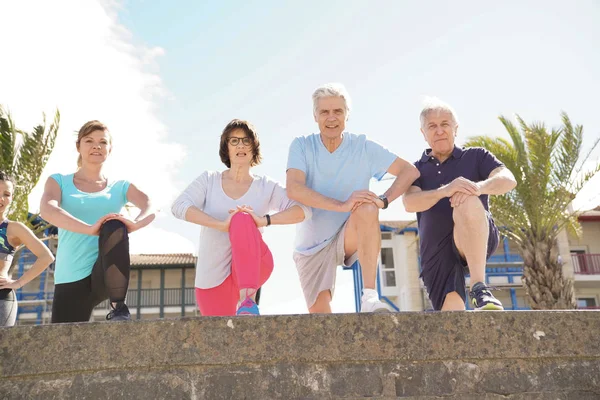 Gruppo Anziani Che Allungano Sulla Spiaggia Con Coach Girl — Foto Stock