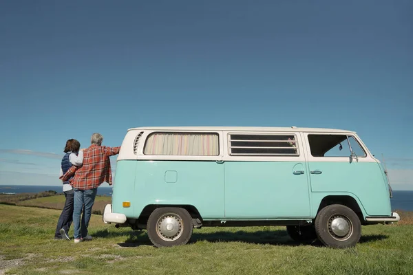 Back view of senior couple leaning on vintage van and looking at the Ocean