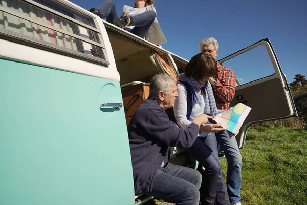 Senior people on a road trip with camper van reading map