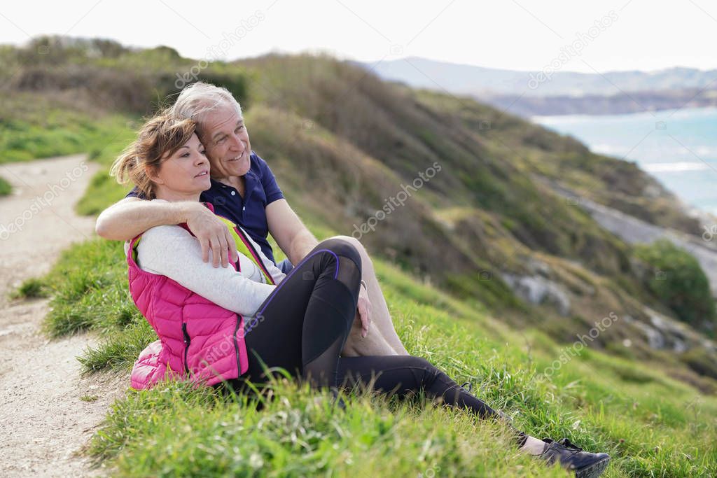 Senior couple relaxing by the coast admiring the ocean view