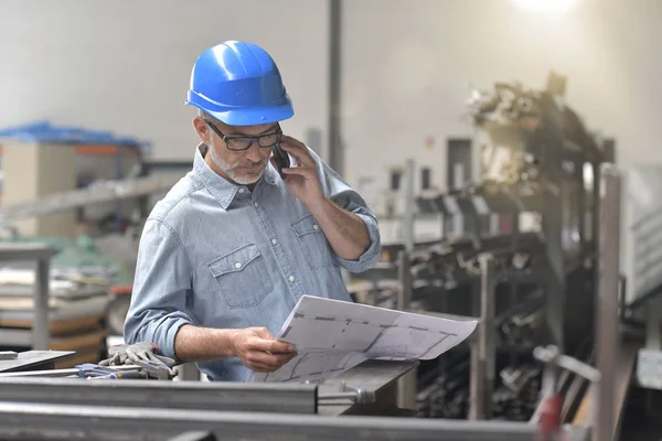 Metallurgy engineer talking on phone in factory