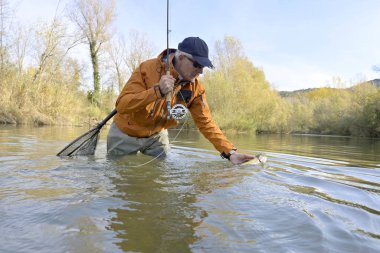 Sonbaharda bir balıkçı tarafından gökkuşağı alabalığının yakalanması