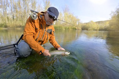 Sonbaharda bir balıkçı tarafından gökkuşağı alabalığının yakalanması