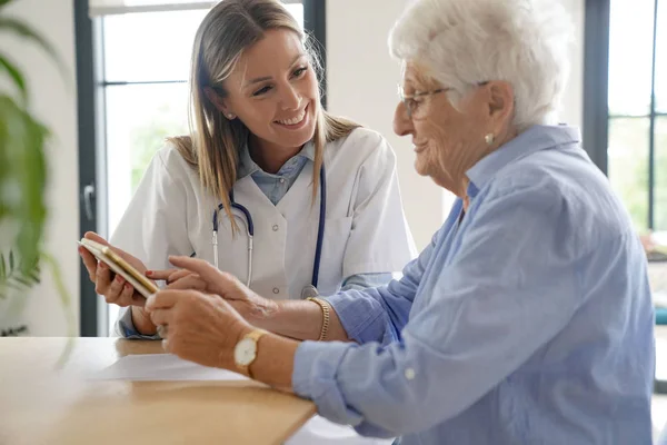 Äldre Kvinna Med Sjuksköterska Hemma Tittar Tabletten — Stockfoto