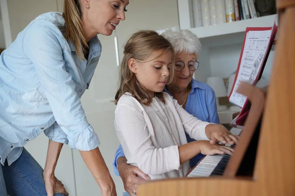 ピアノを弾いている女の子 お母さんとおばあちゃん彼女を見て — ストック写真
