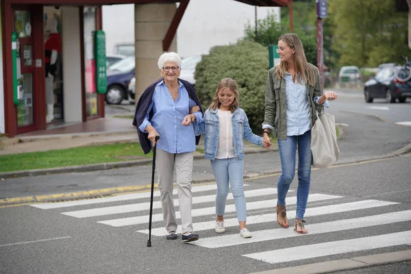 Grandmother, mother and daughter crossing the street