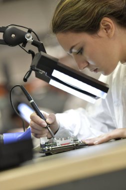 Mikro elektronik laboratuarında çalışan genç bir kadın çırak.