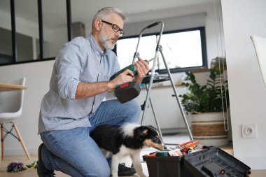 Evdeki adam köpek yavrusuyla tek başına iş yapıyor.