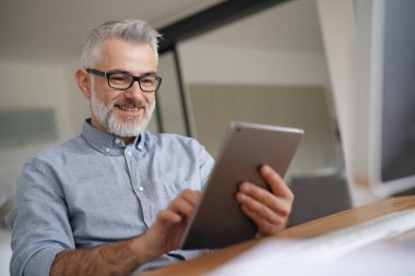 Dijital tabletle çalışan olgun bir adam