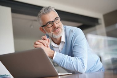 ofiste dizüstü bilgisayarda çalışan adam