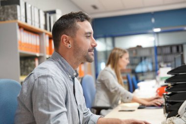 Ofisteki satıcı masaüstü bilgisayarı üzerinde çalışıyor