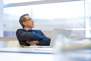 İş yerindeki iş adamı laptopun önünde düşünceli davranıyor.