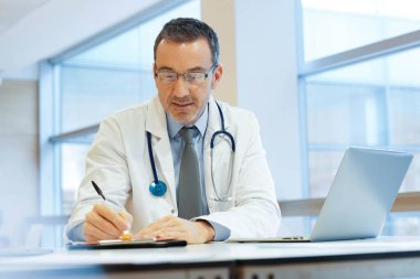 Hastanedeki doktor dizüstü bilgisayarla çalışıyor.