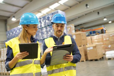 Workers in warehouse controlling incoming merchandise clipart