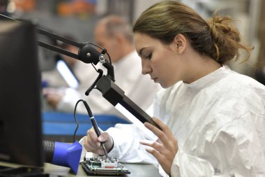 Mikro elektronik laboratuarında çalışan genç bir kadın çırak.