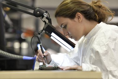 Mikro elektronik laboratuarında çalışan genç bir kadın çırak.