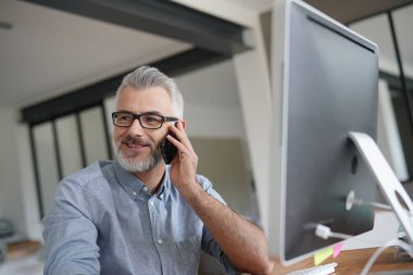Ofisteki olgun adam telefonda konuşuyor. 