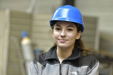 Çelik fabrikasının güvenlik kasklı çırağının portresi.