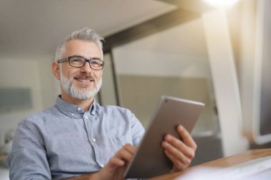 Dijital tabletle çalışan olgun bir adam