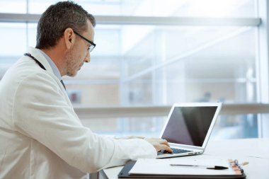 Hastanedeki doktor dizüstü bilgisayarla çalışıyor.