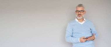 Tablet kullanan orta yaşlı bir adam, gri arka planda izole edilmiş - şablon