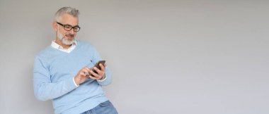 Akıllı telefon kullanan orta yaşlı bir adamın portresi.