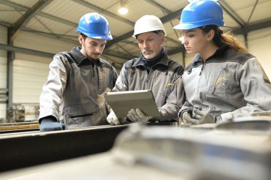 Atölyede genç bir çırağı olan çelik işi eğitmeni.