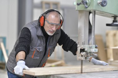 Marangoz odun kesmek için makine kullanıyor.