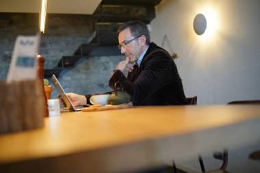 Kahve dükkanında dizüstü bilgisayarla çalışan bir iş adamı.