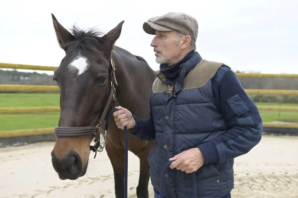 Portrait of horseman standing by horse