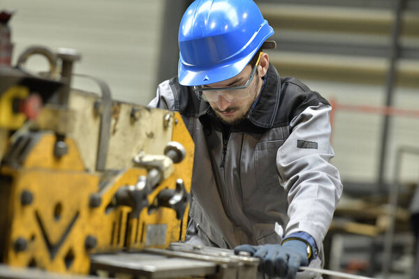 Young apprentice using steelworks machine