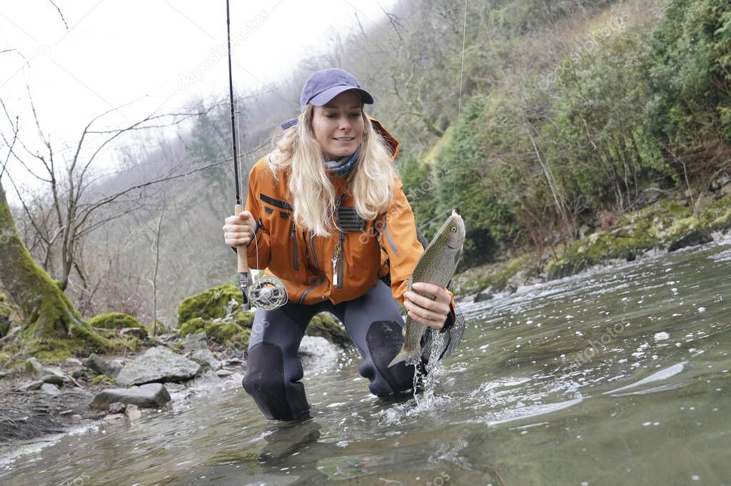 woman fly fishing catching rainbow trout