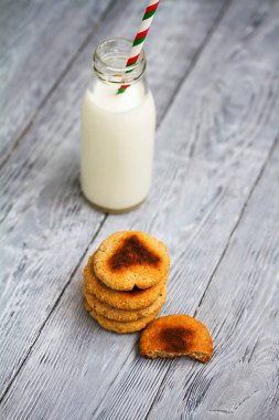 Kırmızı şeritli payet ve ahşap arka plan üzerinde çip çerezler ile süt şişe