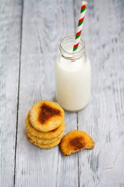 Kırmızı şeritli payet ve ahşap arka plan üzerinde çip çerezler ile süt şişe