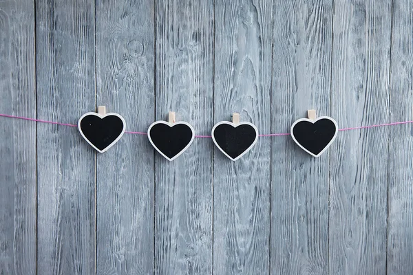 Little black  hearts on a rope  on a pink rope on a wooden gray background
