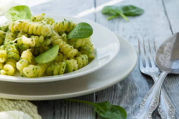 Delicious pasta dish with creamy spinach sauce decorated with spinach leaves on grey wooden background — Stock Photo, Image