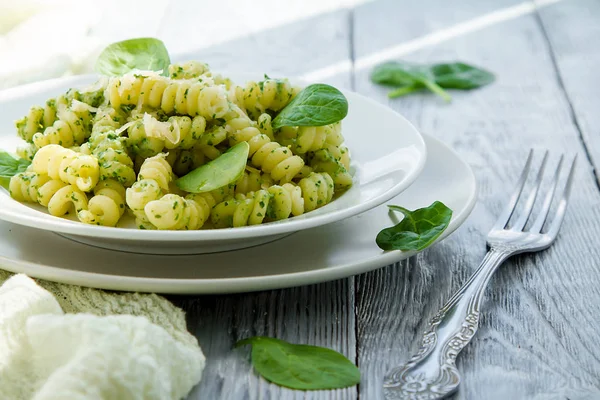 Delicious pasta dish with creamy spinach sauce decorated with spinach leaves on grey wooden background — Stock Photo, Image