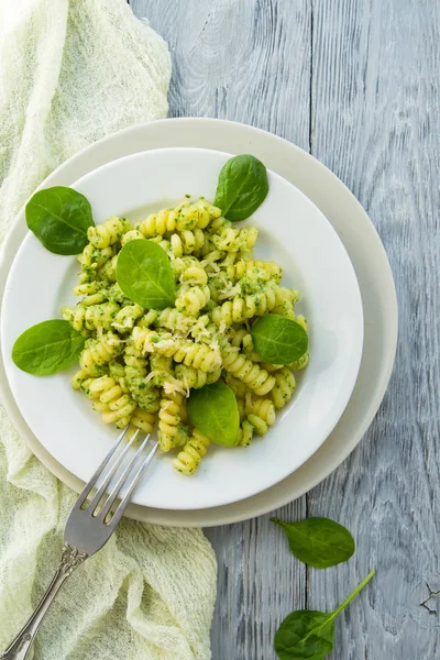 Delicioso plato de pasta con salsa de espinacas cremosa decorada con hojas de espinaca sobre fondo de madera gris — Foto de Stock