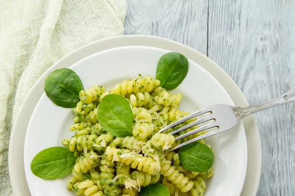 Delizioso piatto di pasta con salsa di spinaci cremoso decorato con foglie di spinaci su sfondo di legno grigio — Foto Stock