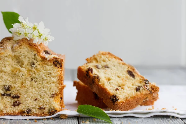 Homemade tasty cut cake with raisins and cherry flowers on a grey wooden table