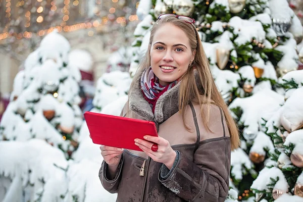 Mujer joven sonriente leyendo en una tableta en el invierno en la calle — Foto de Stock