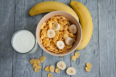 Sağlıklı kahvaltı, bir bardak süt, muz ve mısır gevreği.