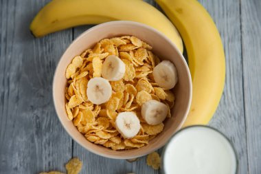 Sağlıklı kahvaltı, bir bardak süt, muz ve mısır gevreği.