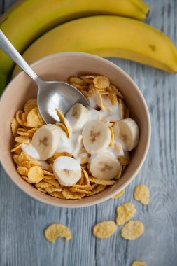 Sağlıklı kahvaltı, bir bardak süt, muz ve mısır gevreği.