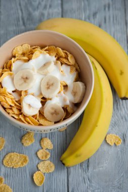 Sağlıklı kahvaltı, bir bardak süt, muz ve mısır gevreği.