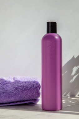 Mor Terry kumaşı ya da havlu ve vücut bakımı için duş jeli ve şampuanı olan bir kozmetik şişe. Spa tedavileri ve vücut bakımı.