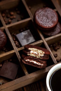 Kahveli tatlı atıştırmalık. Beyaz fincan kahve ve yarısı yenmiş çikolatalı turta. Çikolatalı turtaya odaklan.