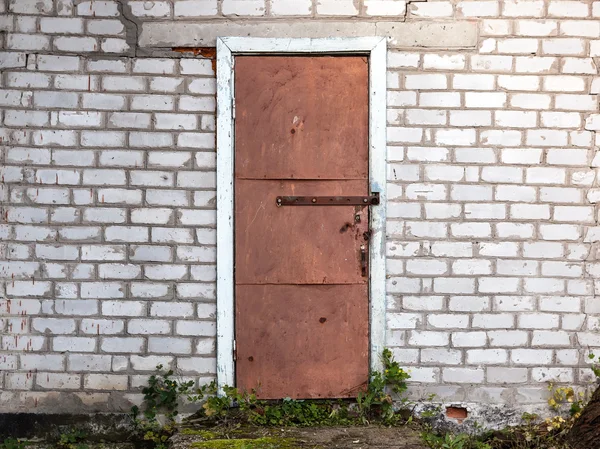 Oude verweerde schuur deur en bakstenen muur. — Stockfoto